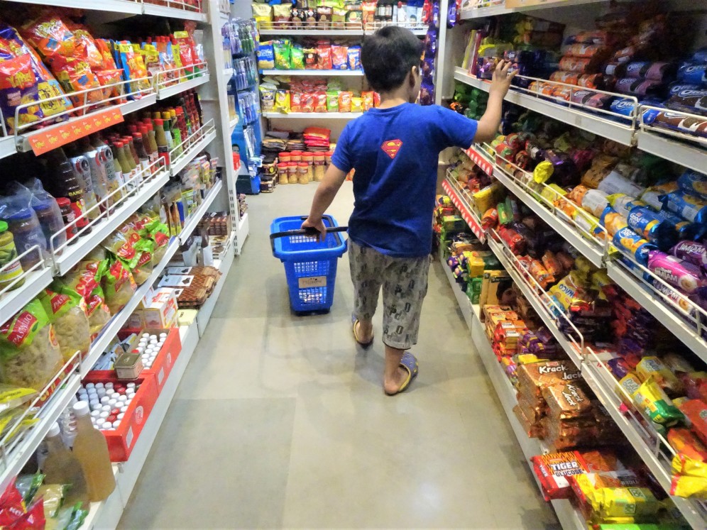 Criança em corredor com doces em supermercado